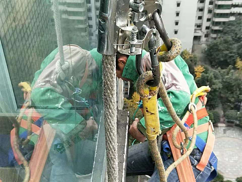 高空外墻施工：1、目前外墻粉刷主要有兩種方式：吊板方式和吊籃方式。 2、吊板方式是用吊繩、吊板將人吊到工作位置進行清洗。一般的大樓都可以用這種方式進行清洗，但是這種方式的操作必須使安全措施到位，否則危險性很大，造成傷亡事故的都是因安全措施不到位造成的。 3、墻面破損、裂縫、不平整等部位在底涂前用外墻耐水膩子修補平整。每次批刮膩子的厚度控制在2mm之內(nèi)，批刮膩子的總厚度不超過5mm。膩子應(yīng)堅實牢固，不得粉化、起皮或干裂。 4、干后，要用砂紙打磨平整，再用濕布將膩子上的浮灰抹去，并盡快涂漆，以免再次落灰。