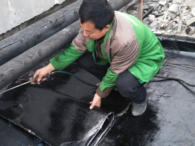 屋頂貼防水卷材：首先做好基礎(chǔ)準(zhǔn)備工作，清理基層，施工前將驗(yàn)收合格的基層表面塵土、建筑雜物清理干凈。接著涂刷基層處理劑，高聚物改性瀝青卷材施工，攪拌均勻后，用長(zhǎng)把滾刷均勻涂刷于基層表面上，常溫經(jīng)過(guò)4h后，開始鋪貼卷材。熱熔封邊，將卷材搭接處用噴槍加熱，趁熱使二者粘結(jié)牢固，以邊緣擠出瀝青為度；末端收頭用密封膏嵌填嚴(yán)密。防水層蓄水試驗(yàn)，卷材防水層完工后，確認(rèn)做法符合設(shè)計(jì)要求，將所有雨水口堵住，然后灌水，水面應(yīng)高出屋面最高點(diǎn)20㎜，24h后進(jìn)行認(rèn)真觀察，尤其是管根、風(fēng)道根，不滲不漏為合格，否則應(yīng)進(jìn)行返工。