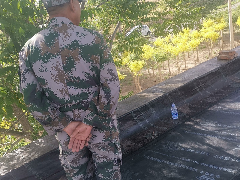 屋頂防水卷材鋪貼:清除基層表面雜物、油污、砂子，凸出表面的石子、砂漿疙瘩等應(yīng)清理干凈，清掃工作必須在施工中隨時進(jìn)行，并修補(bǔ)平整表面。尤其鏟除排水口、煙囪、管壁上的水泥砂漿等附著物；根據(jù)施工現(xiàn)場狀況，進(jìn)行合理定位，確定卷材鋪貼方向，在基層上彈好卷材控制線，依循流水方向從低往高進(jìn)行卷材試鋪。卷材試鋪后，先將要鋪貼的卷材剪好，反鋪于基面上(即是底部隔離紙朝上)，撕剝?nèi)ゾ聿母綦x紙。撕剝時，已剝開的隔離紙宜與粘結(jié)面保持45～60度的銳角，防止拉斷隔離紙，盡量保持在自然松弛狀態(tài)，但不要有皺折。