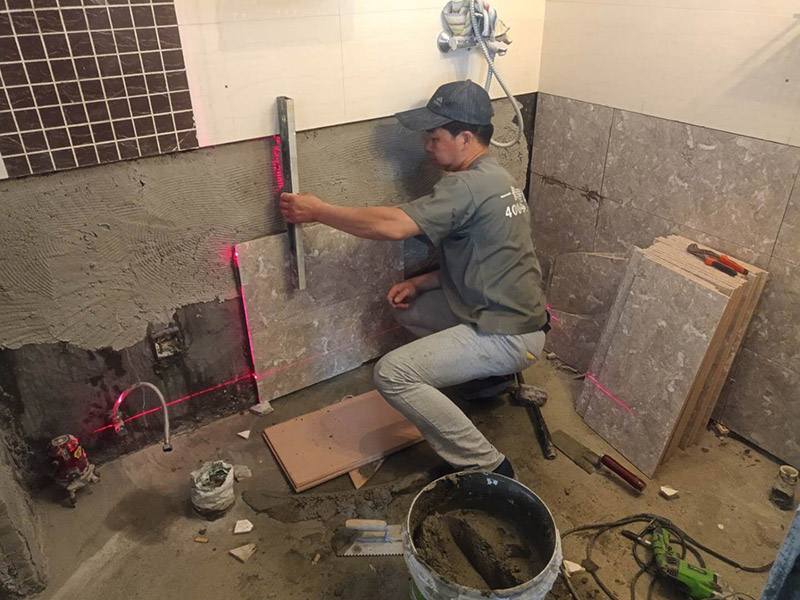 衛(wèi)生間貼磚施工：施工工藝流程; 基層處理--抹底子灰--彈線排磚--侵磚--鑲貼--擦縫--交工驗(yàn)收 用一比三的水泥砂漿打底,打底厚度5~~7mm，待底子灰干六七成干時(shí)候，按圖紙要求，進(jìn)行彈線，排磚。立好皮數(shù)桿，排磚形式有主要兩種直縫和錯(cuò)縫。當(dāng)?shù)孛嬗蟹核臅r(shí)候，注意安排好泛水。侵泡瓷磚，時(shí)間不少于兩個(gè)小時(shí)，陰干通常是3~~5小時(shí)。瓷磚在鑲貼時(shí)候，瓷磚下口坐在八字尺或直尺上。鋪貼的方式有離縫和無(wú)縫。鑲貼瓷磚從陽(yáng)角開始，自下向上貼，瓷磚背面刀灰，貼上用力壓，用鏟刀木柄輕輕敲打，鋪貼時(shí)候砂漿飽滿，缺灰重貼，不得塞灰，貼6~~8塊，用靠尺校正。水管處先鋪周圍整塊磚，后鋪異型磚。最后擦縫。