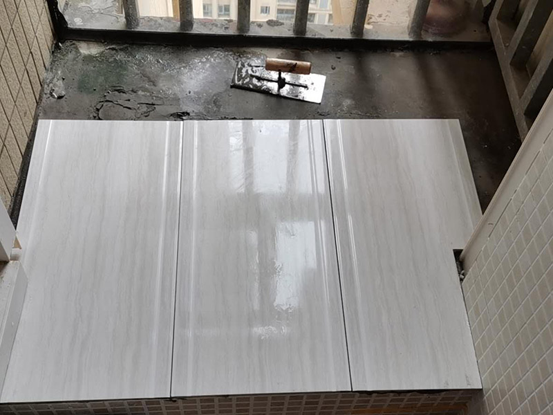 陽臺瓷磚鋪貼：準備粘結(jié)劑前，瓷磚不應浸水，但要用鋼絲刷除去磚背面的松散物質(zhì)，并用濕布抹去磚背的浮塵。然后按照生產(chǎn)商建議的比例將水或乳液放到攪拌桶中攪拌直至粘結(jié)劑均勻無結(jié)塊。初始攪拌后的粘結(jié)劑應靜置在攪拌桶中，直到生產(chǎn)商推薦的熟化時間過后攪拌一下再使用。 在鋪壓瓷磚前，在瓷磚背面也批一薄層粘結(jié)劑。這種雙批法雖然用的材料和工時比較多，但卻能夠保證粘貼的質(zhì)量和耐久性。 在粘結(jié)劑量置晾時間內(nèi)，將準備好的瓷磚鋪壓到位，垂直于梳理方向輕微搓動以排出磚下的空氣。鋪貼到位后用橡皮錘輕擊，用尺寸合適的十字定位架來調(diào)整表面平整度及接縫的平直。