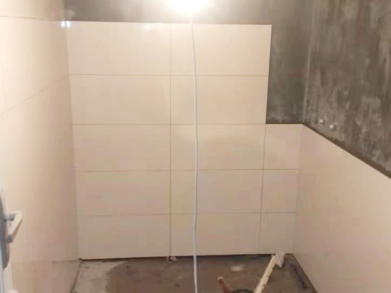 衛(wèi)生間墻面貼磚：首先應除去基層表面的污垢，油漬，浮灰;除去基層上所有涂料層，膩子層;如果基層未能達到平整度要求，需對基層進行預先的找平處理。鋪貼瓷磚前需事先找好垂直線，以此為基準鋪貼的瓷磚高低均勻、垂直美觀;此外，施工前在墻體四周需彈出標高控制線，在地面彈出十字線，以控制地磚分隔尺寸。對瓷磚的色彩、紋理、表面平整等進行嚴格的挑選，然后按照圖紙要求預鋪。對可能出現(xiàn)的尺寸、色彩、紋理誤差等進行調(diào)整、交換，直至達到最佳效果。 調(diào)制粘結(jié)劑：加水后將粘結(jié)劑漿料攪拌至潤滑均勻，無明顯塊狀或糊狀結(jié)塊，攪拌后的漿料靜置5-10分鐘后再稍加攪拌1-2分鐘即可使用。 將瓷磚平整地鋪貼在基層上，使用橡膠錘將瓷磚拍實鋪平。施工過程中，可小幅度轉(zhuǎn)動瓷磚，使?jié){料與瓷磚背面充分接觸。