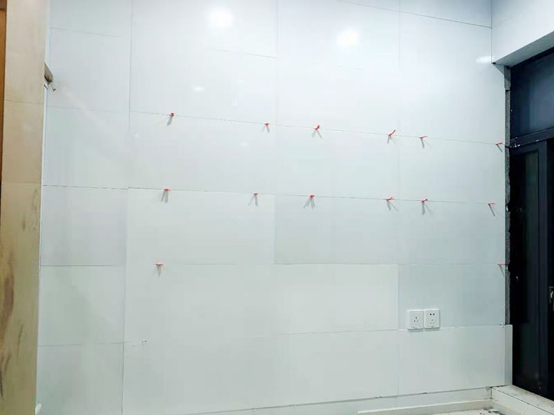 墻磚鋪貼施工：基層處理：保持墻面的平滑，踢平表面凹凸不平的位置或用1:3比例的水泥漿抹平，用鐵絲擦掉殘留的灰塵、油漬、砂漿等。 找標(biāo)高、彈線：根據(jù)水平控制線和設(shè)計(jì)圖紙劃出標(biāo)高，再拋出十字線并保持墻面一線和地面一線垂直。 預(yù)鋪：在圖紙?jiān)O(shè)計(jì)要求的基礎(chǔ)上，嚴(yán)格挑選墻磚的色彩、紋理等，然后進(jìn)行預(yù)鋪，對于預(yù)鋪效果中可能出現(xiàn)的紋理、尺寸、色差進(jìn)行調(diào)整、更換，直到達(dá)到最佳效果。 貼磚：貼磚選用1：3比例的干硬性水泥砂漿，砂漿厚度2cm左右。鋪貼前將墻磚背面濕潤，正面保持干燥。把墻磚輕輕地放在水泥砂漿上，用手錘輕敲瓷磚表面直至緊密平整即可。 勾縫、擦縫：在貼完磚24小時后進(jìn)行勾縫工作，采用同一品種的水泥漿或?qū)Ｓ锰羁p劑進(jìn)行空隙填補(bǔ)，使墻磚最終緊密嚴(yán)實(shí)，最后再擦凈多余的水泥或填縫劑。